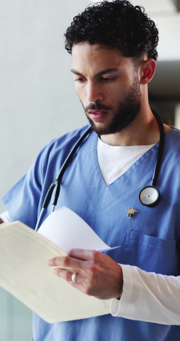 Male Nurse Reviewing Medical Records in Hospital Corridor
