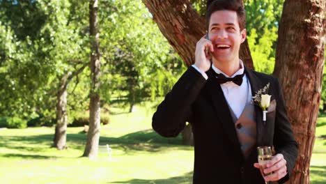 Happy-groom-drinking-champagne-and-chatting-on-phone