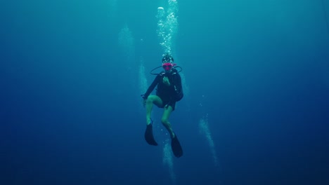 scuba diver explores deep blue ocean with exhaled bubbles