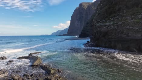 Blue-ocean-and-sea-next-to-the-cliffs-and-a-cobblestone-beach-with-the-waves-calming-coming-into-the-beach-on-a-slightly-over-casted-day