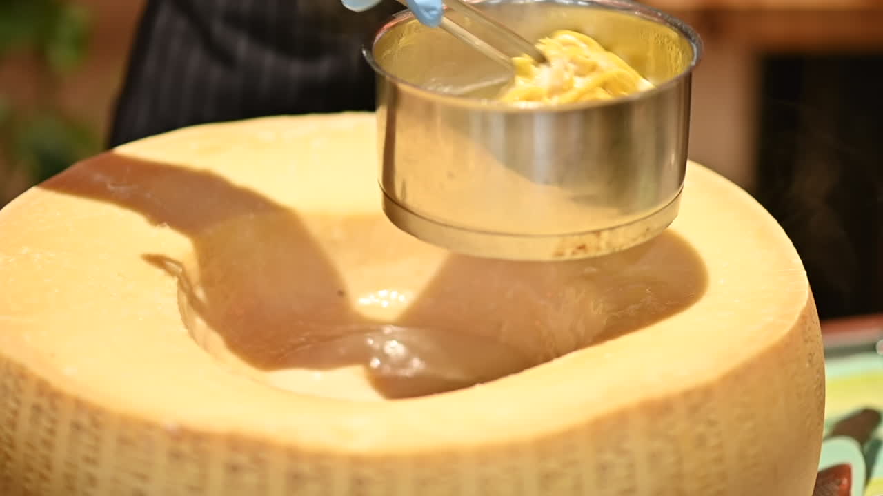 Man putting pasta in a heated parmesan wheel at a restaurant