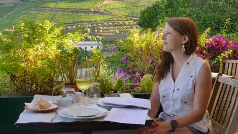 a woman at the restaurant overlooking terrace vineyards at douro valley, portugal