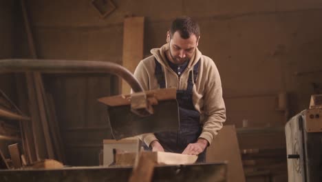 frente, cerca de las imágenes de la madera de aserrado en una máquina circular. carpintero en mono