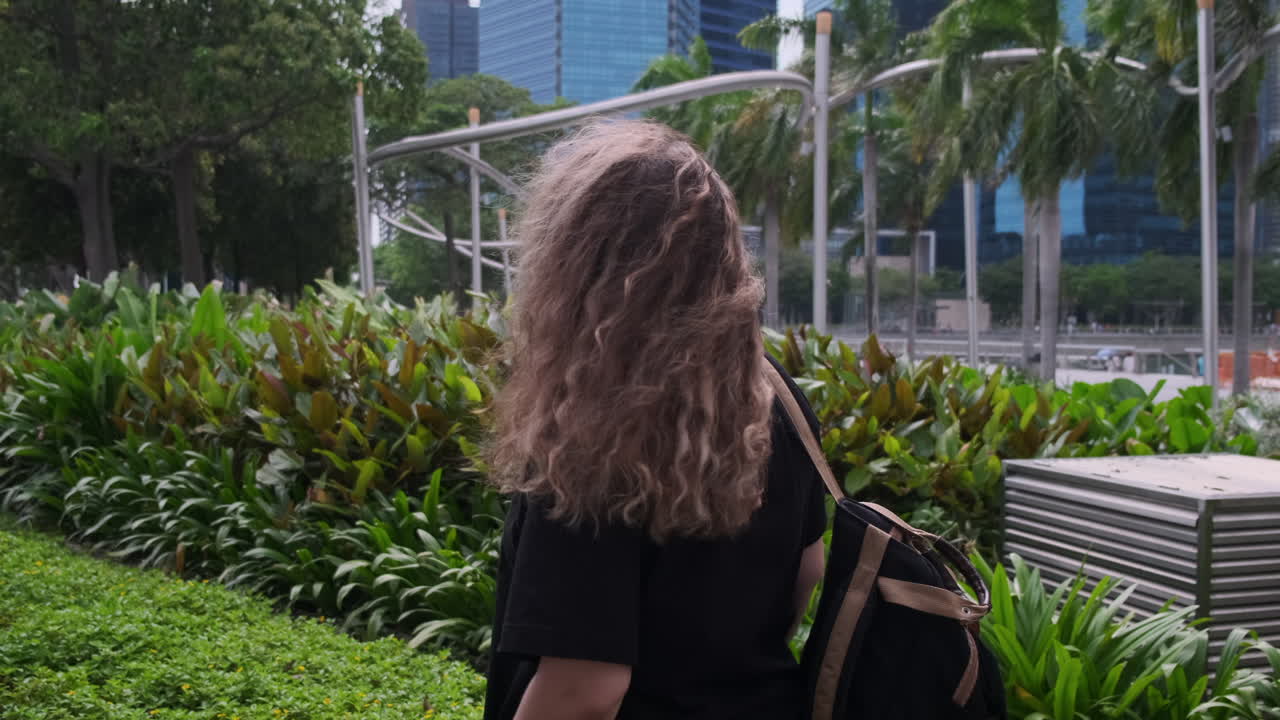 Woman with Curly Hair Walking in a City Park