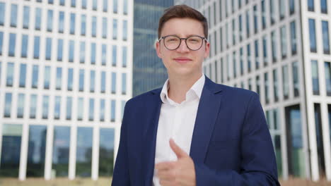 Young-business-man-in-glasses-does-thumbs-up-outdoors,-portrait-shot