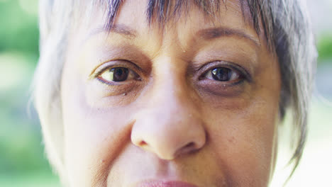 retrato en primer plano de los ojos de una mujer biracial mayor parpadeando en el jardín, en cámara lenta