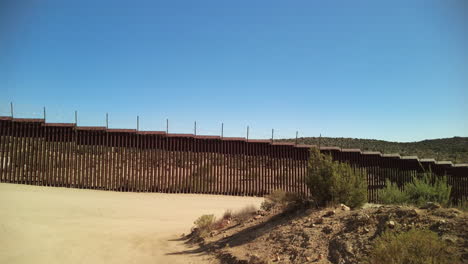 border fence dividing usa and mexico in rural california, panning shot