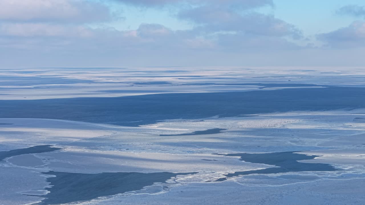 静寂な広大さを感じさせる、曇り空の下に広がる凍結した海