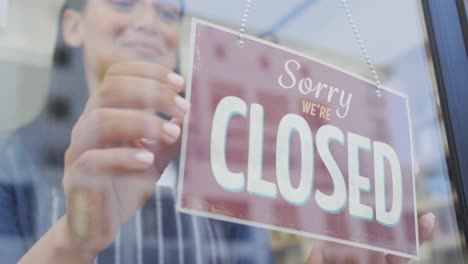 animation of happy biracial waitress turning banner on doors at coffee shop