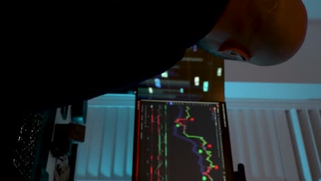 Over-The-Shoulder-Shot-Of-Home-Day-Trader-Looking-At-Interconnected-computer-screens-in-dark-room