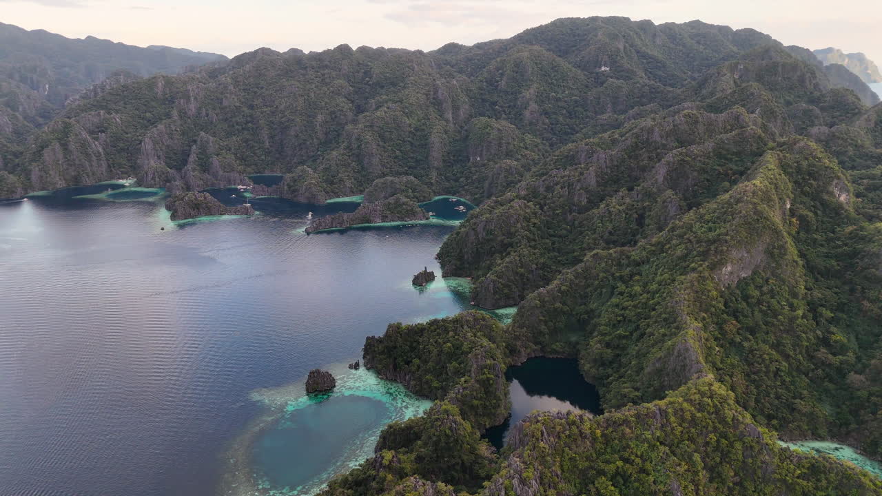 Aerial drone view of Coron Island’s dramatic cliffs, tropical greenery, and idyllic turquoise waters, Philippines. Wide rotating shot.