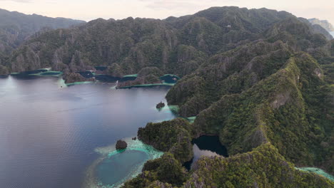 aerial drone view of coron island’s dramatic cliffs, tropical greenery, and idyllic turquoise waters, philippines. wide rotating shot.