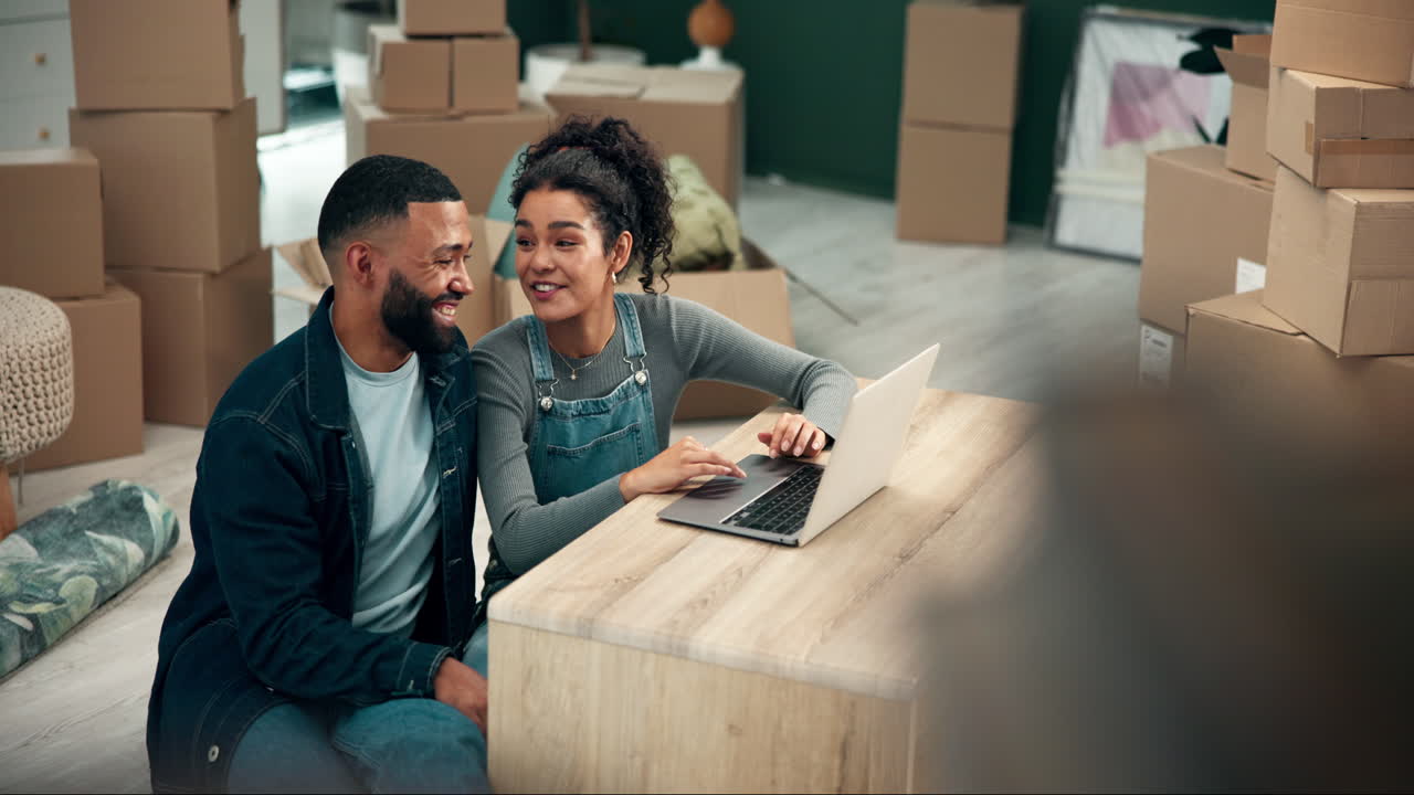 Couple planning move in new home surrounded by boxes using laptop