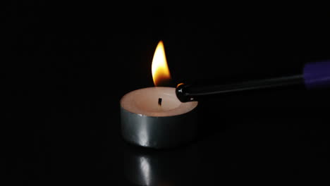 un encendedor encendiendo una vela de luz de té
