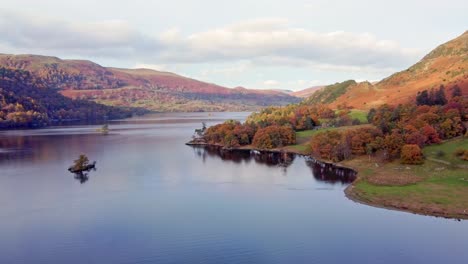 scenic drone view of colourful autumn lake district lake scene with forrest and island