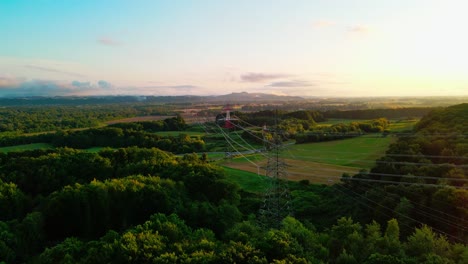 Atemberaubende-4K-Drohnenaufnahmen-Eines-Hochspannungsturms-Im-Hintergrund-Bei-Sonnenuntergang