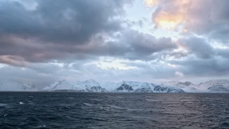 mysterious, mountainous coastline visible from the turbulent waters of the norwegian sea