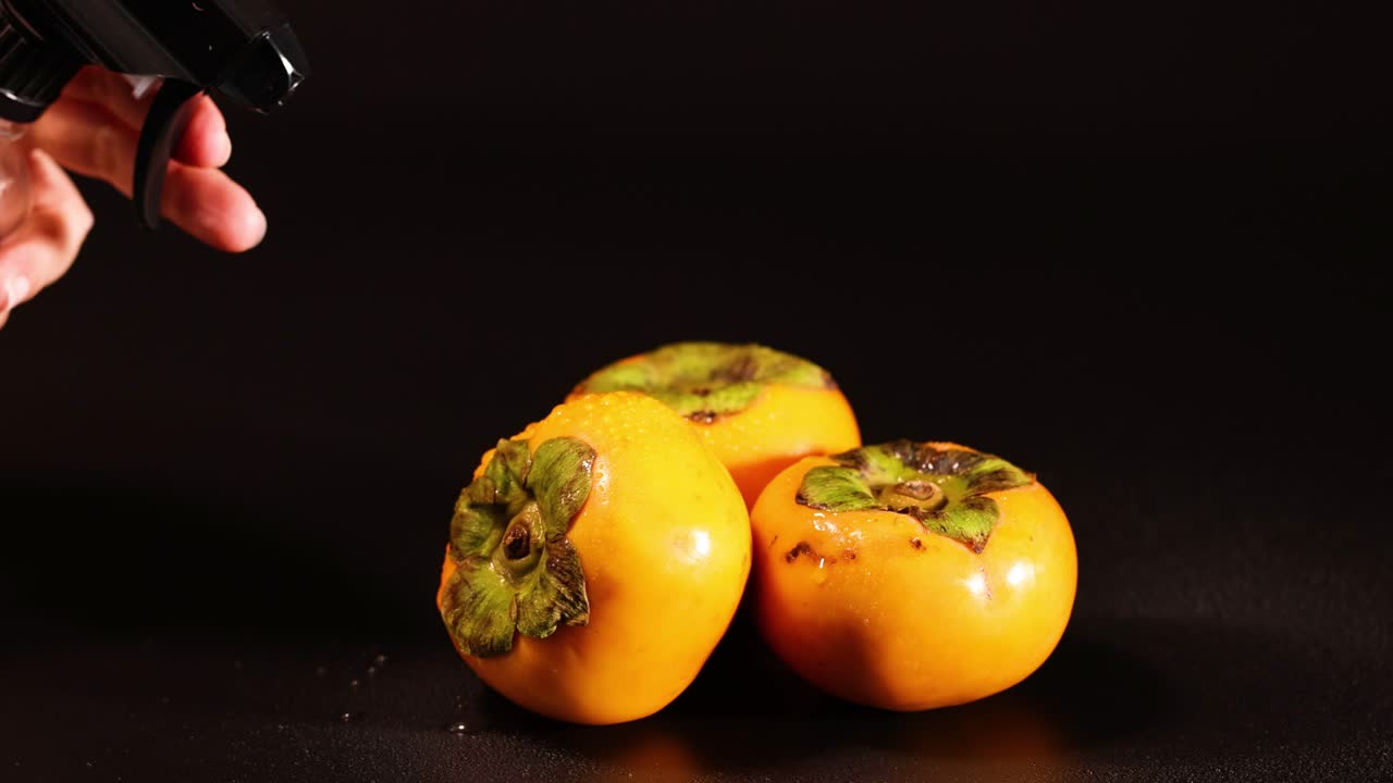 pulverización de agua en persimiones contra un fondo oscuro