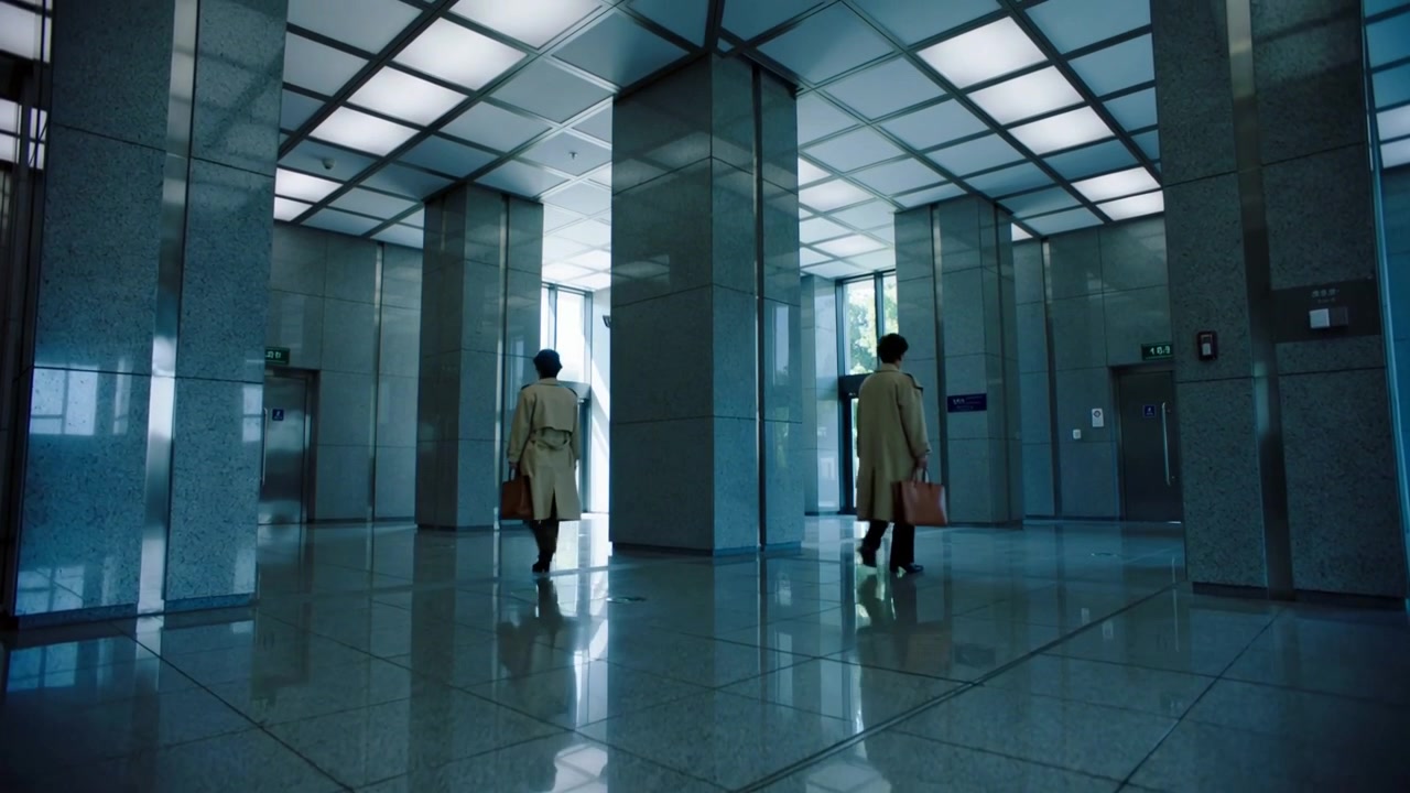 Entrando nella hall, due uomini in cappotti beige si dividono dirigendosi verso l'ascensore e l'uscita in vetro, portando valigette.