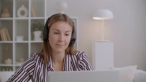 young female specialist of call-centre or tech support is answering using headphones with microphone