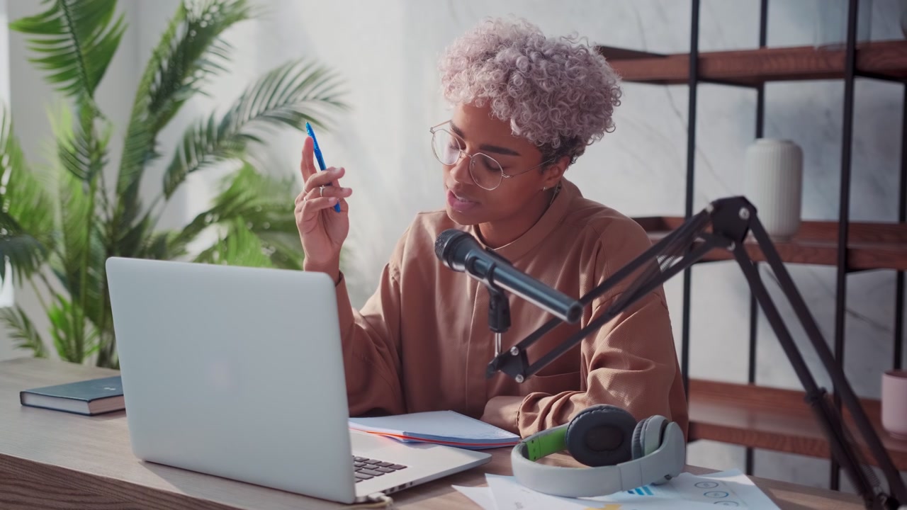 Young african american woman hosting audio podcast with laptop studio microphone