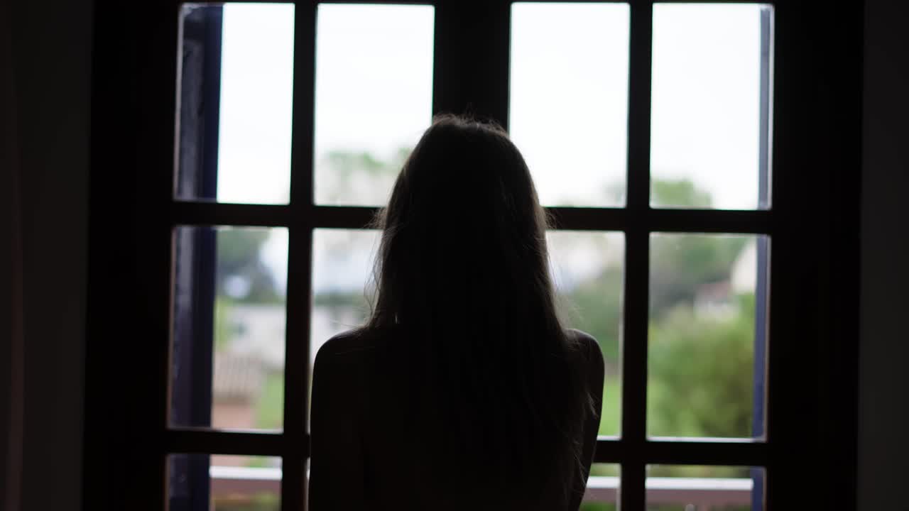 방에서 커튼을 열고 발코니로 나가는 여자