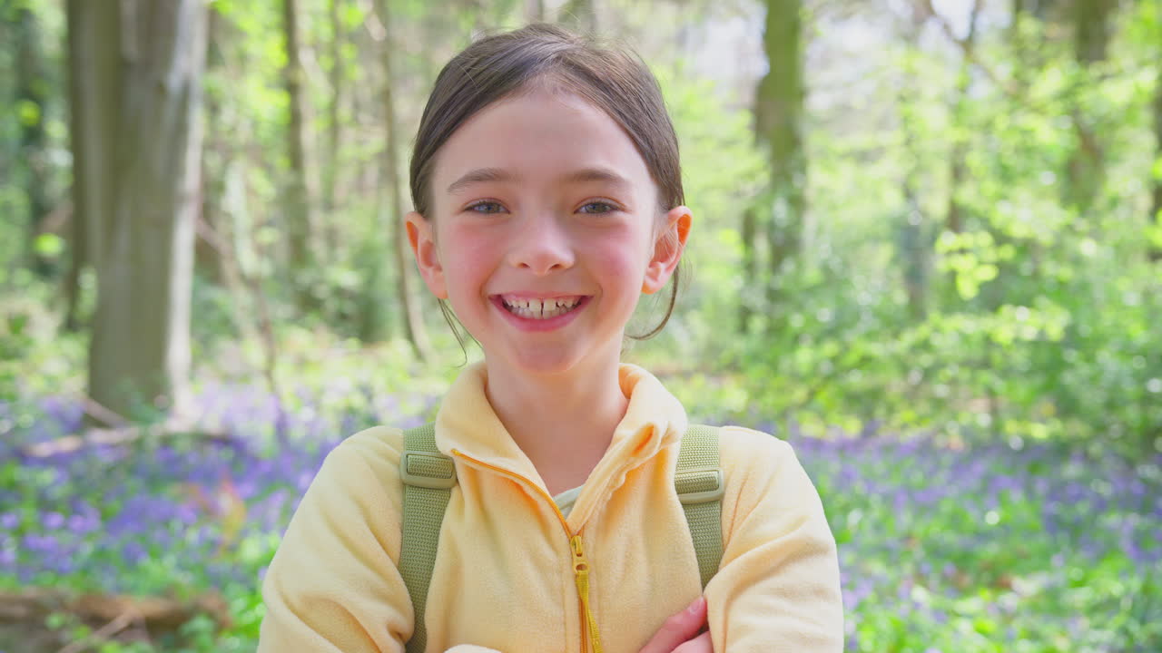 Portrait Of Smiling Girl Walking In Spring Woodlands With Bluebells