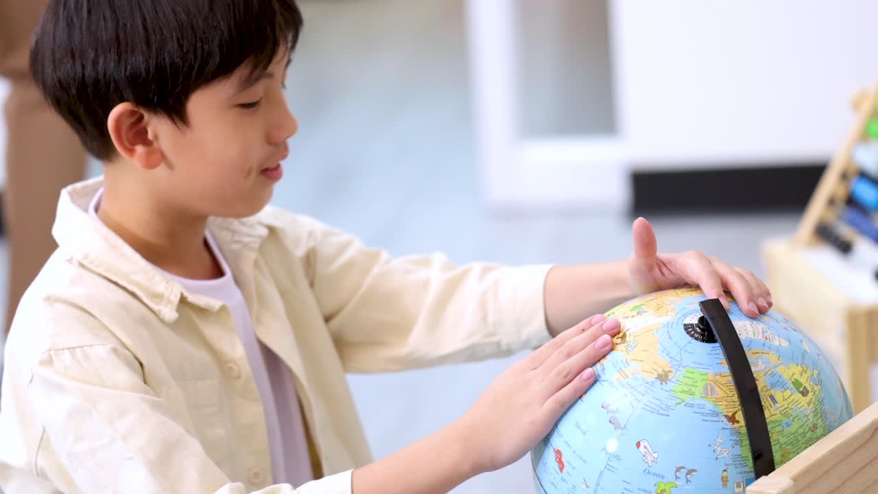 好奇心旺盛な学生が明るい教室でカラフルな地球儀を調べています。近くには支援的な先生がいます。