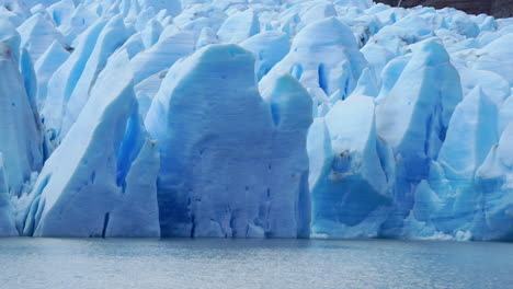glaciar azul derritiéndose lentamente en un lago gris