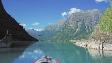 Kayaking-in-the-turquoise-waters-of-the-Loenvatnet-Lake,-forest-covered-mountains-tower-on-both-sides-of-the-lake