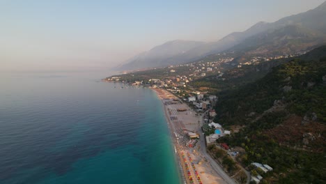 Beach-of-Dhermi-with-umbrellas-and-resorts-on-shore-washed-by-blue-turquoise-sea-water