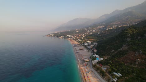 beach of dhermi with umbrellas and resorts on shore washed by blue turquoise sea water