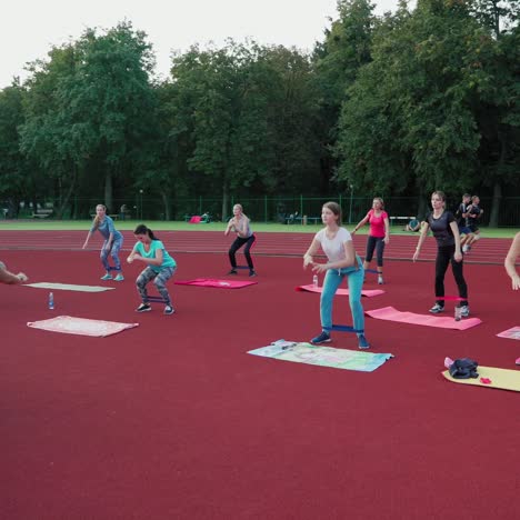 female team training on the outdoor stadium. group of women doing exercises with fitness rubber on the modern sports ground. healthy lifestyle.
