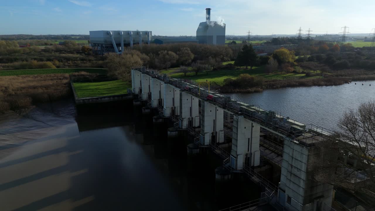Panoramica aerea dell'infrastruttura Saddlebow Tail Sluice, con focus sulle sue enormi paratoie d'acciaio, difese antiallagamento in cemento e canali fluviali