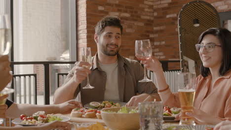 joven hace un brindis con su grupo de amigos en una cena 1