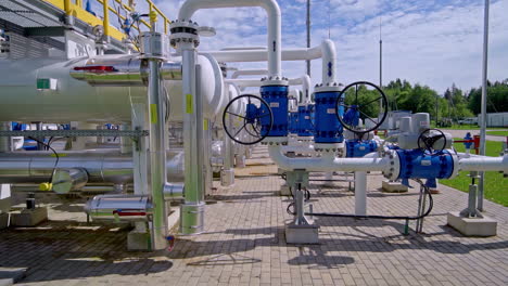large blue control valves on white gas pipelines at an outdoor industrial energy facility