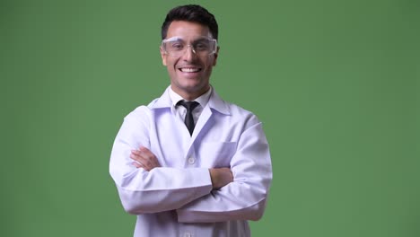 joven hombre hispano guapo médico contra fondo verde
