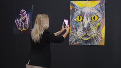 woman taking a picture of art at an exhibit