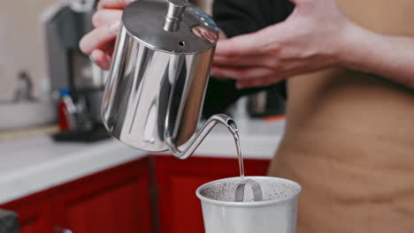 un esperto barista che versa l'acqua con competenza da un bollitore di metallo in una tazza di caffè per la tazza perfetta