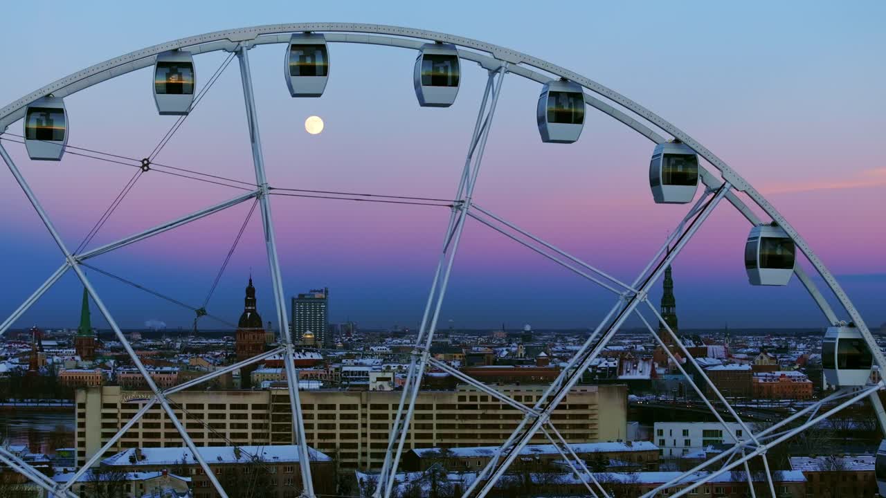Violet and blue skies frame Riga's skyline with a glowing Ferris wheel moonrise