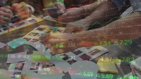 animation of stock market data processing over mid section of graphic designers discussing