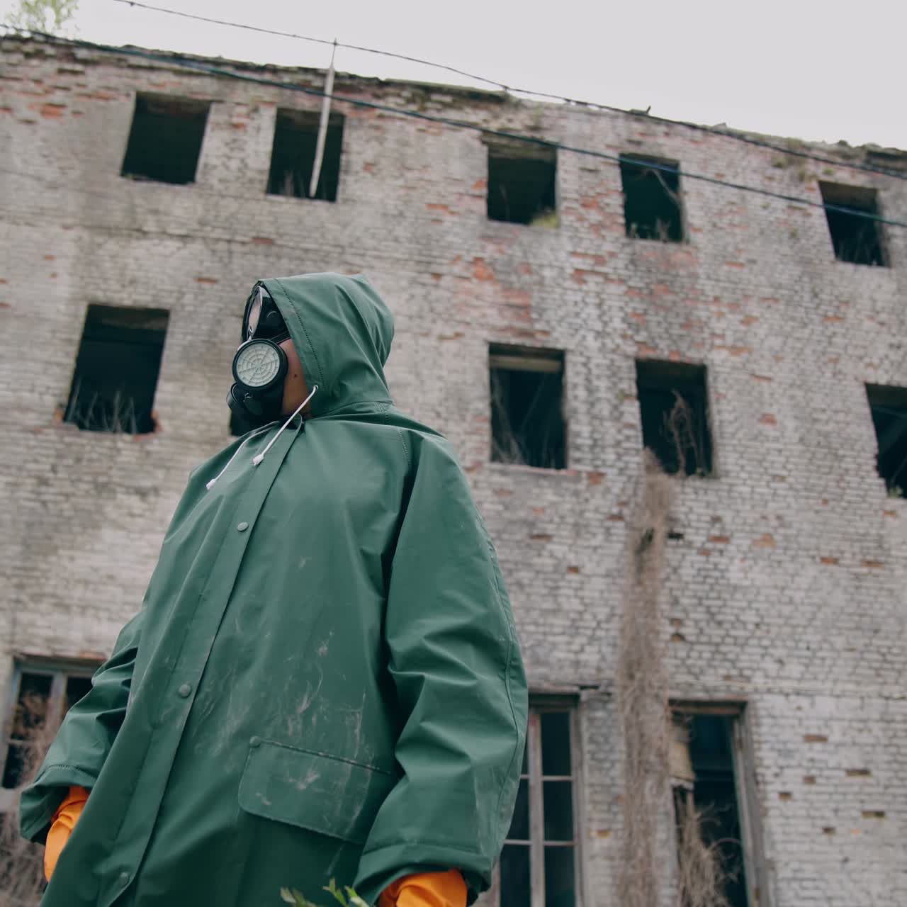Environmentalist in protective suit and gas mask. Man in gas mask near abandoned destroyed building