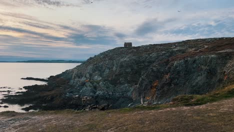 antena del paisaje oceánico con una mujer joven y atractiva tomando fotos de los acantilados de montaña en la costa durante la puesta de sol