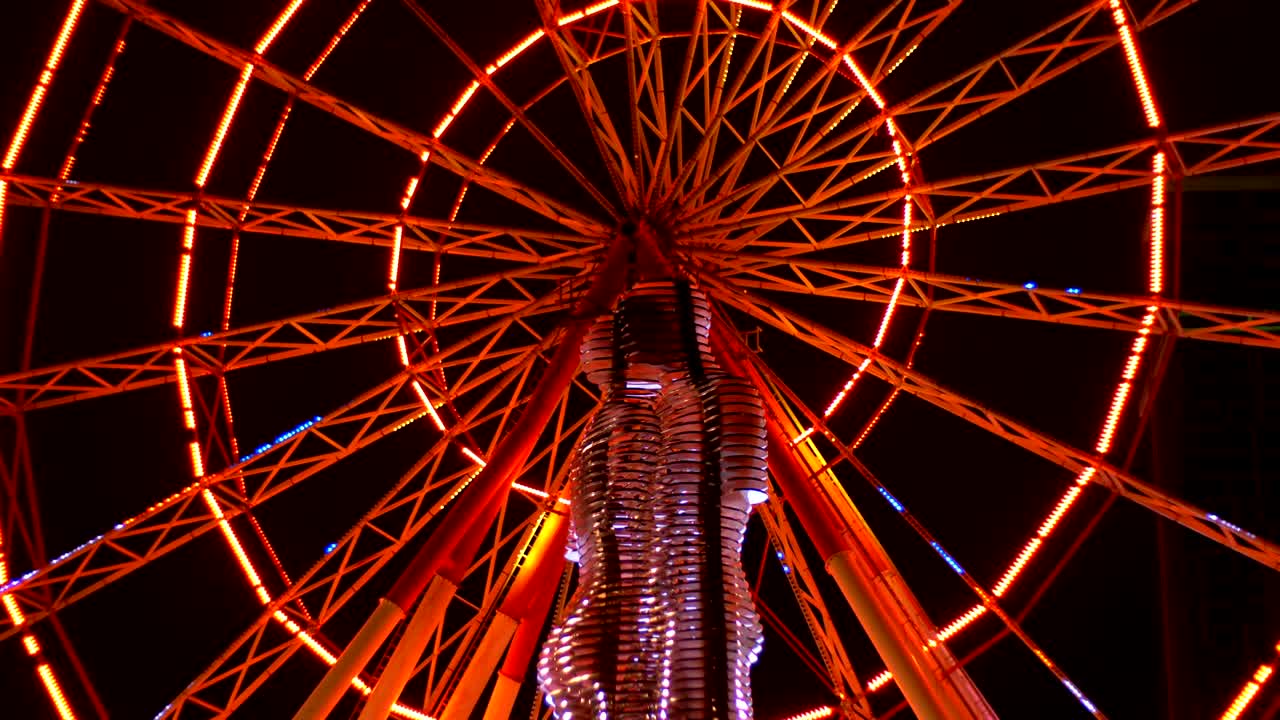 estatua de ali y nino en una rueda de ferris de fondo por la noche en el terraplén de batumi, georgia