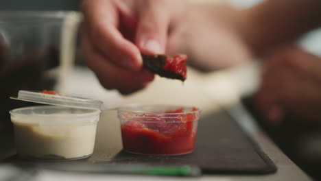 person dipping chips into sauces