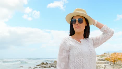 front view of young caucasian woman posing in hat and sunglasses at beach 4k