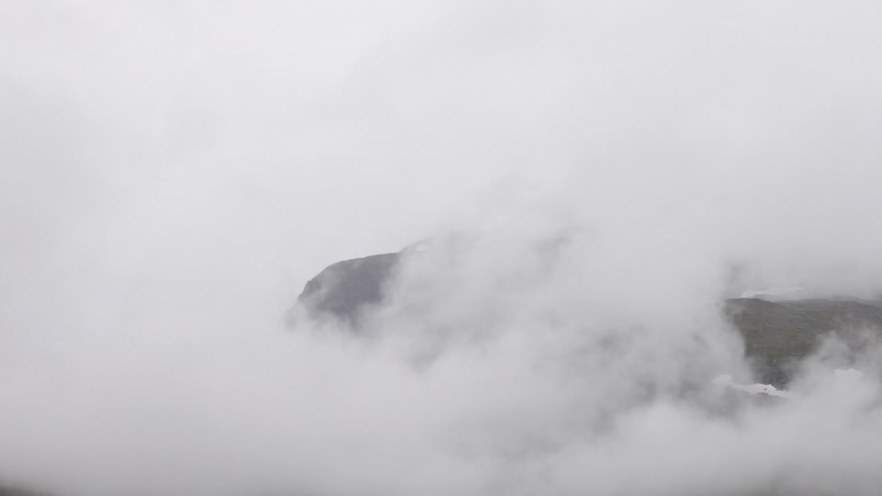Foggy clouds rolling over Dyrhaugstind in Jotunheimen, Norway