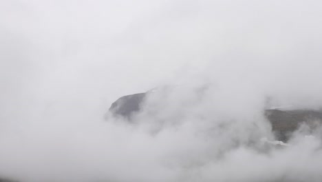 foggy clouds rolling over dyrhaugstind in jotunheimen, norway