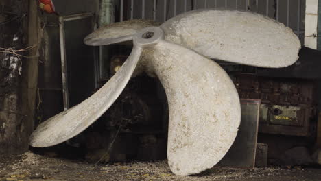 huge used old propeller of ship vessel inside hangar, handheld shot