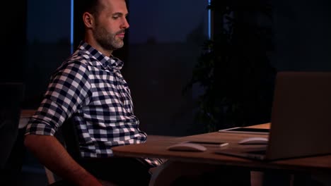 Side-view-of-disabled-businessman-working-late-in-office